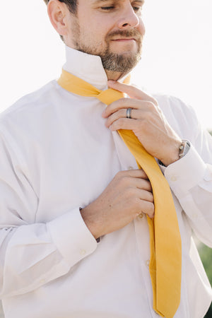 Golden tie worn with a white shirt. 