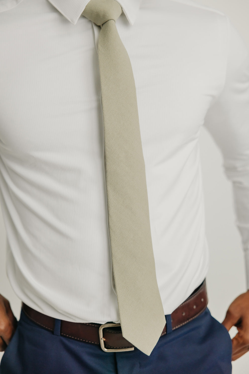 Light Sage tie worn with a white shirt, brown belt and blue pants.