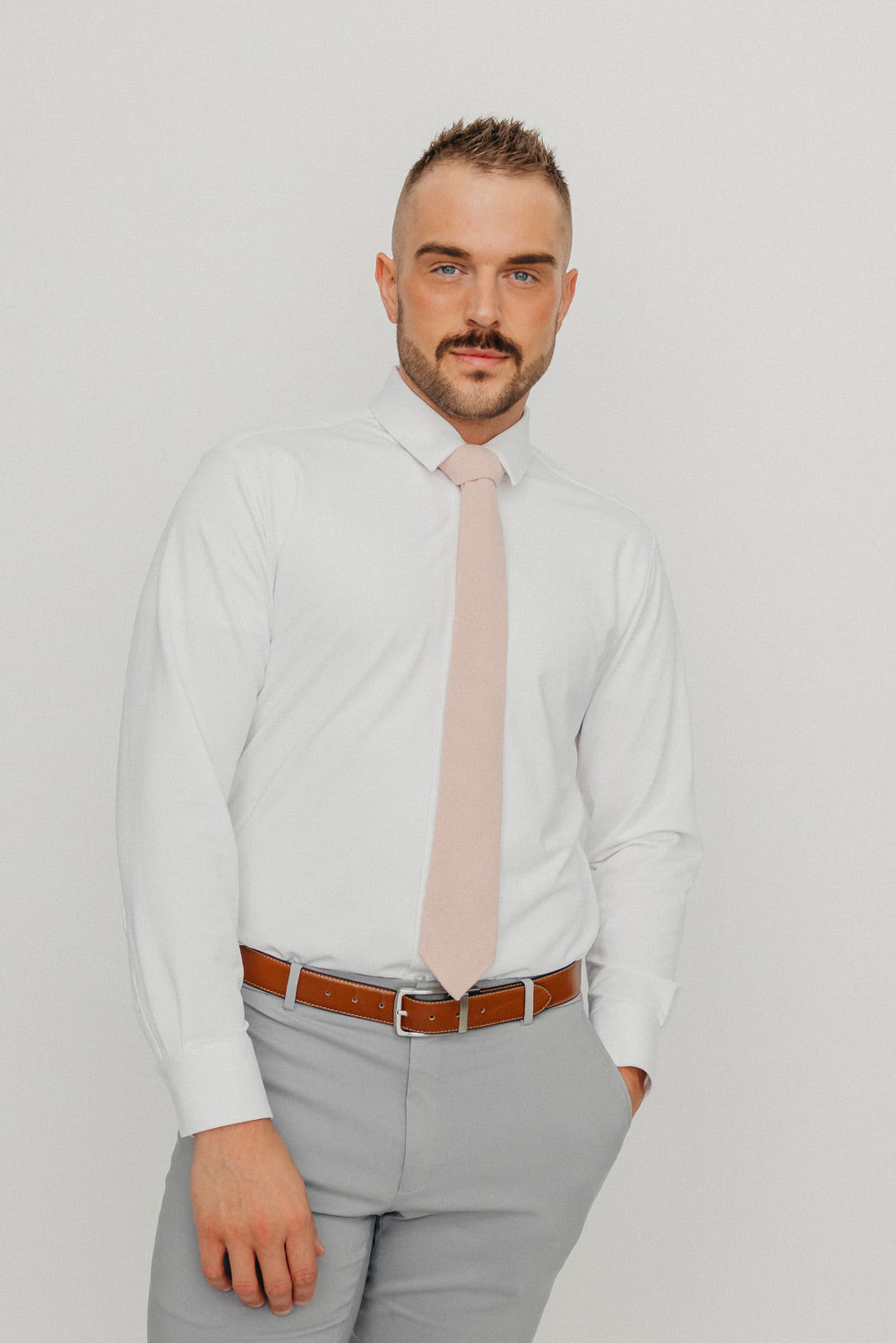Mauve tie worn with a white shirt, brown belt and gray pants.