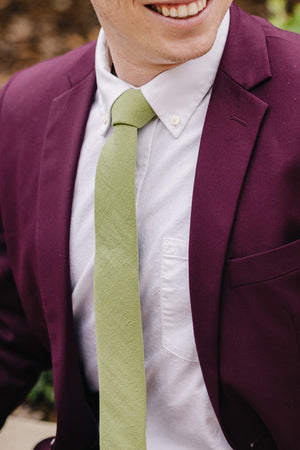 Moss tie worn with a white shirt and plum purple suit jacket.