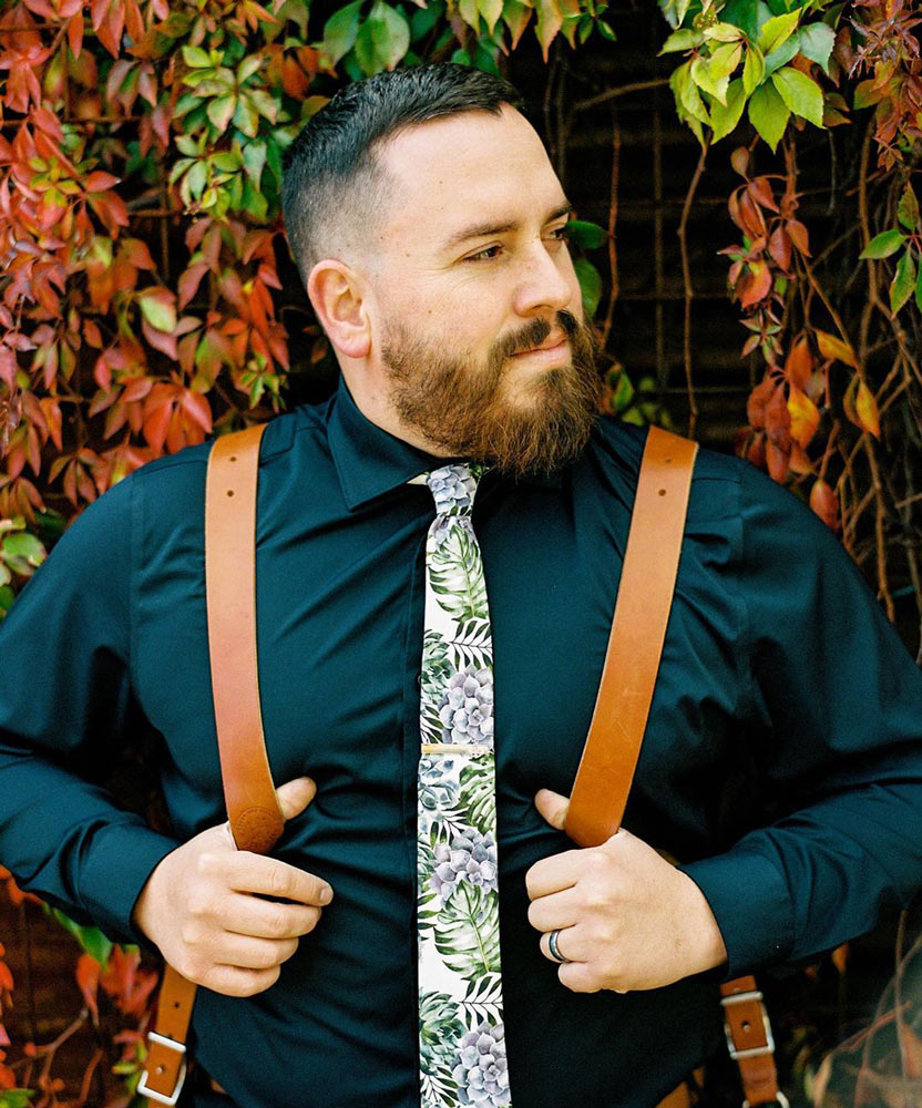 Aloe tie worn with a dark blue shirt and brown suspenders.
