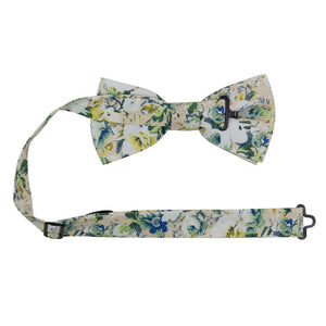 Antiquity Pre-Tied Bow Tie with adjustable neck strap. Off-white cream background with a variety of white, sage green, yellow gold and light navy blue flowers scattered throughout.