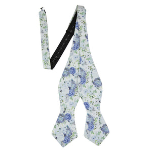 Arctic Ice Self Tie Bow Tie. White background with dusty blue and navy blue flowers and succulents with green leaves.