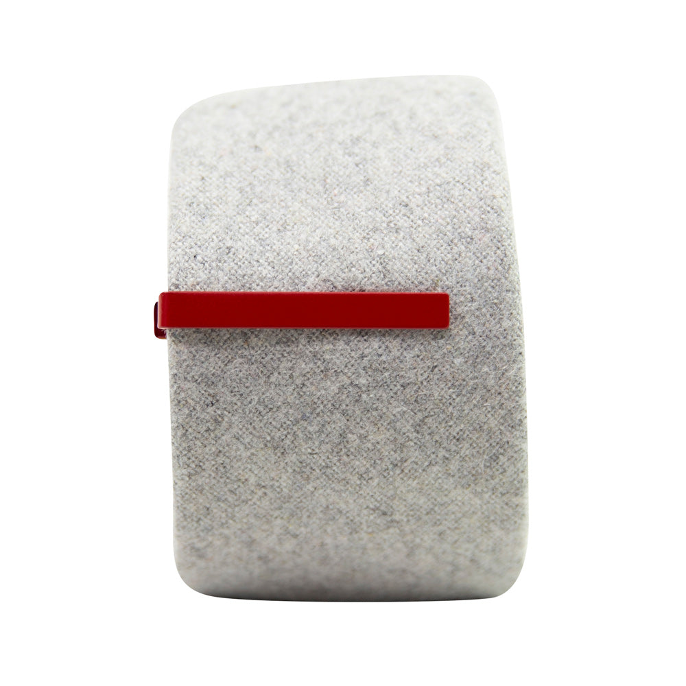Solid cherry red metal tie bar clipped onto a gray textured wool tie that is rolled up.
