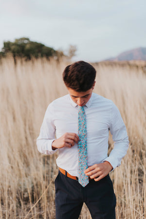 Dahlia tie worn with a white shirt, brown belt and navy blue pants. 