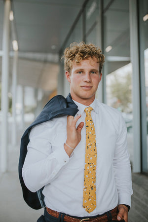 Marigold tie worn with a white shirt and gray patterned suit.