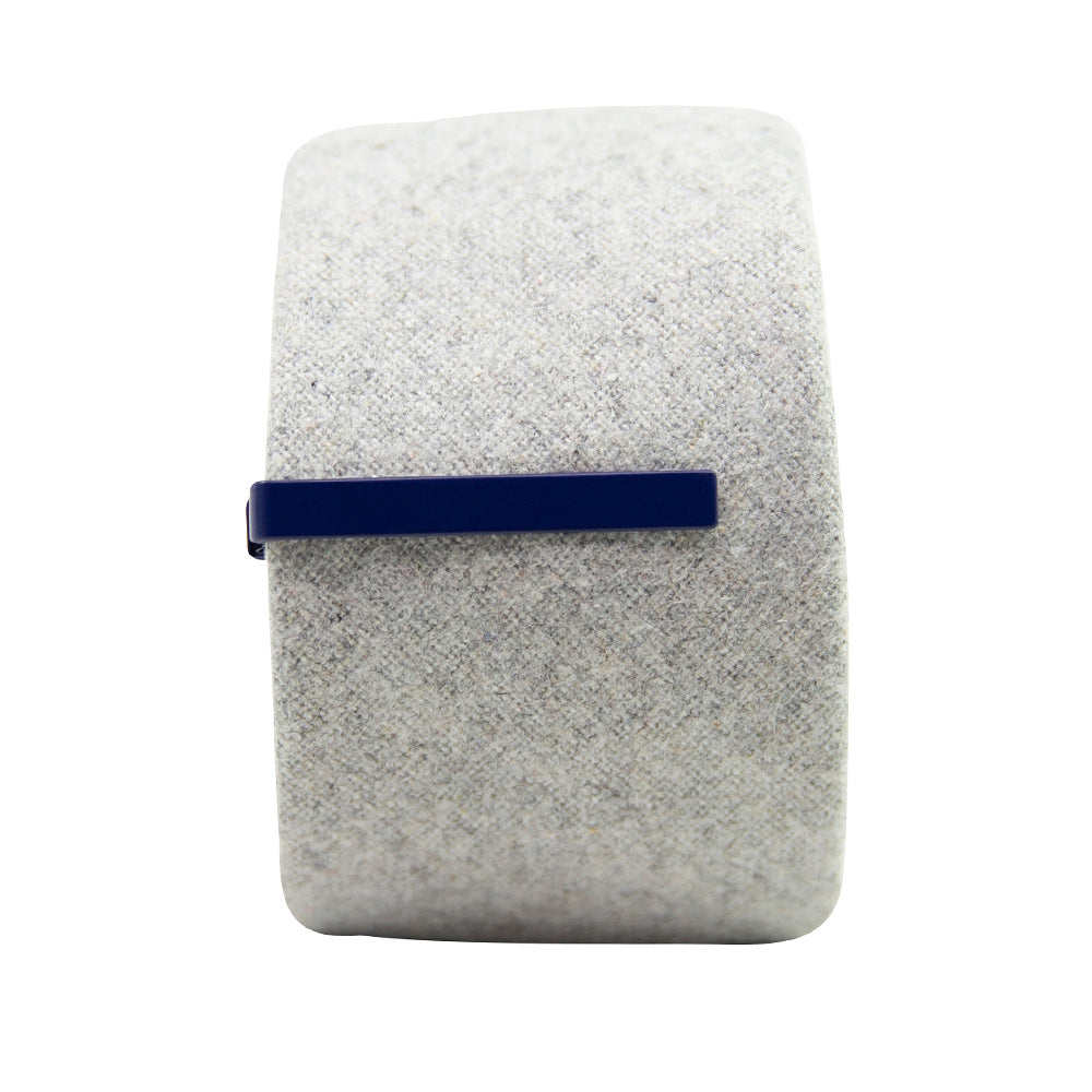 Solid navy blue metal tie bar clipped onto a gray textured wool tie that is rolled up.