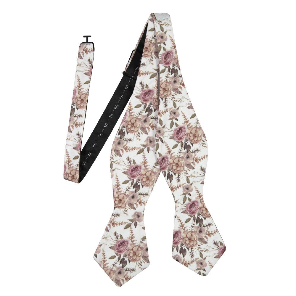 Quicksand Roses Self Tie Bow Tie. White background with mauve, peach and blush pink flowers. Sage green leaves and branches throughout.