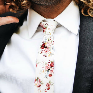 White Floral tie worn with a white shirt and dark charcoal gray suit jacket.