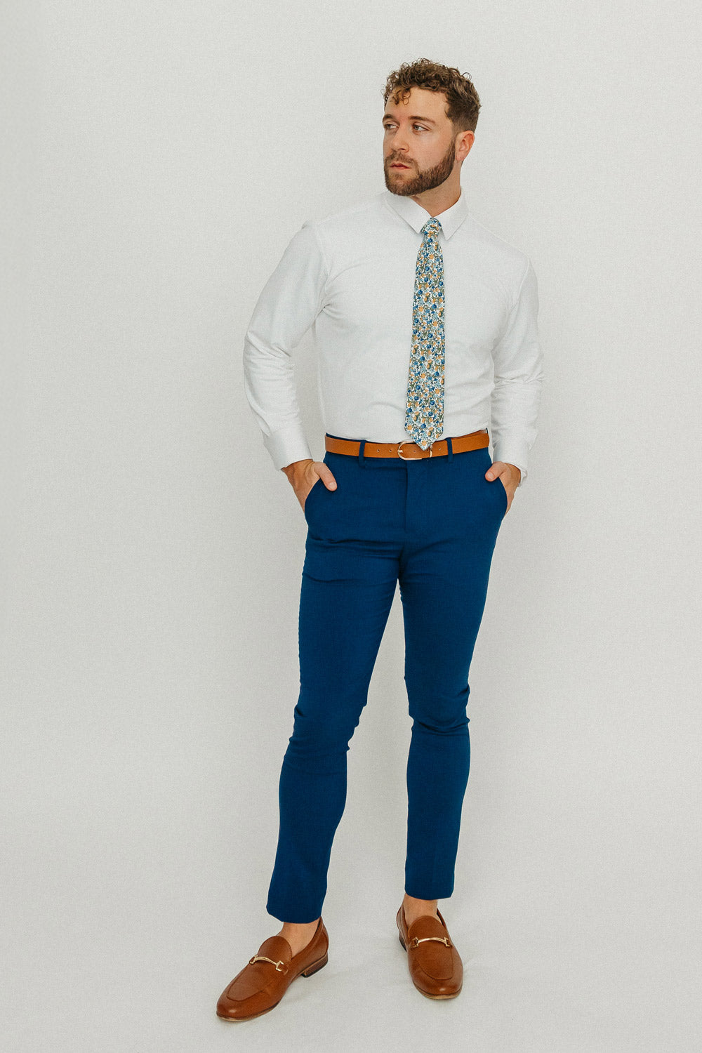 Alpine Blum tie worn with a white shirt, brown belt and blue pants.