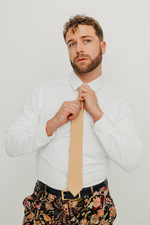 Champagne tie worn with a white shirt, black belt and floral pants.