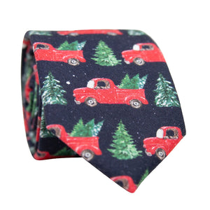 DAZI Forest Fleet Skinny Tie. Navy blue background with red trucks carrying pine trees and small white spots of snow.