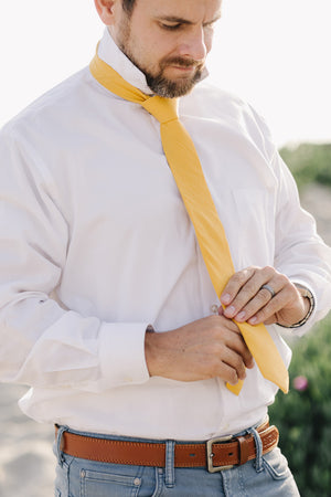 Golden tie worn with a white shirt and blue pants.