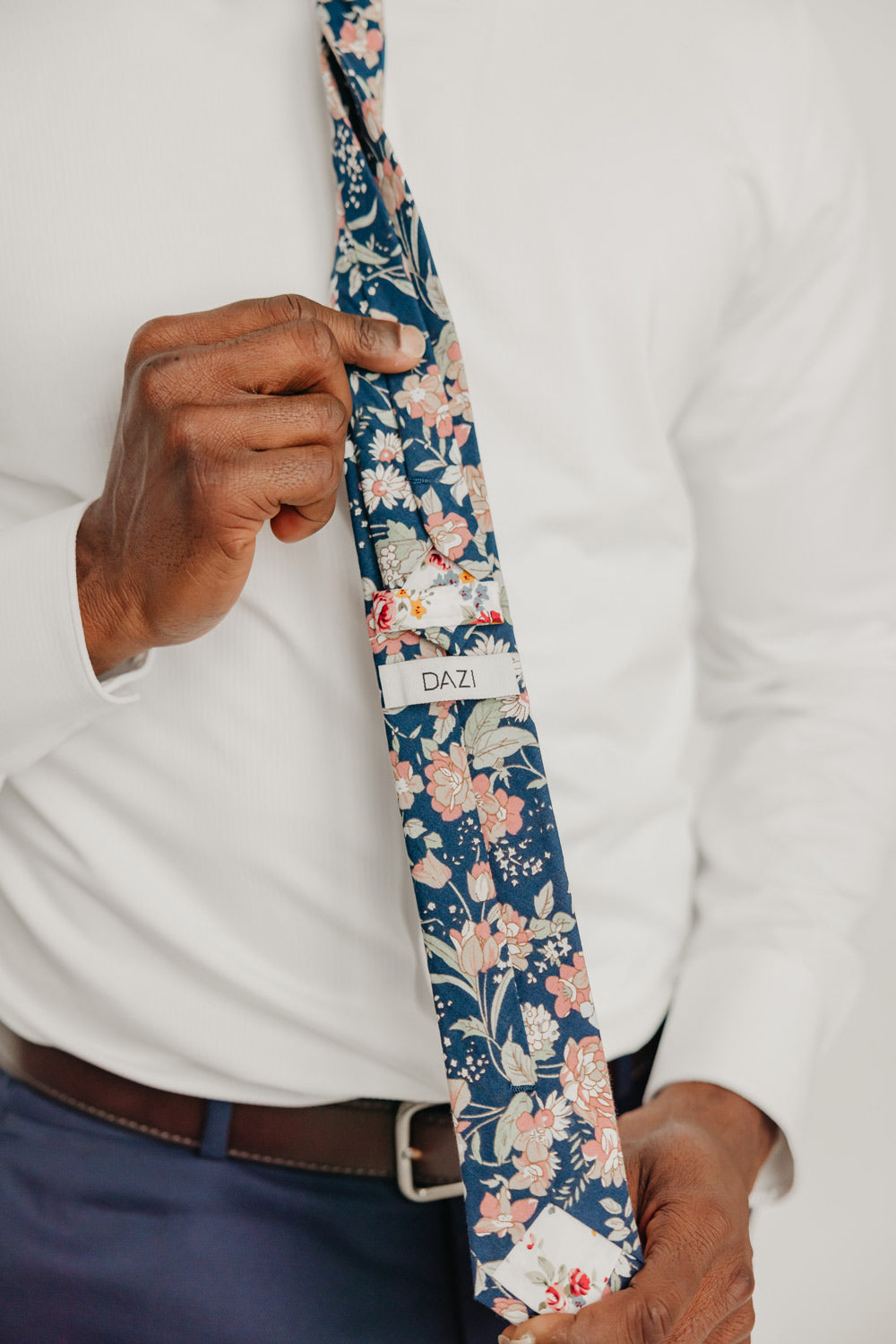 Lotus tie worn with a white shirt, brown belt and blue pants.