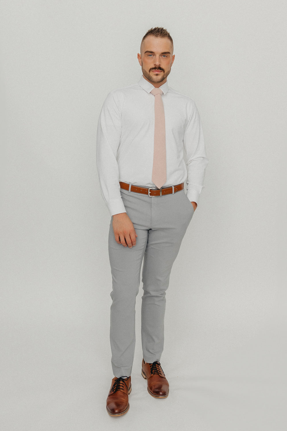 Mauve tie worn with a white shirt, brown belt and gray pants.