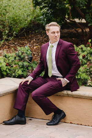 Moss tie worn with a white shirt and plum purple suit.