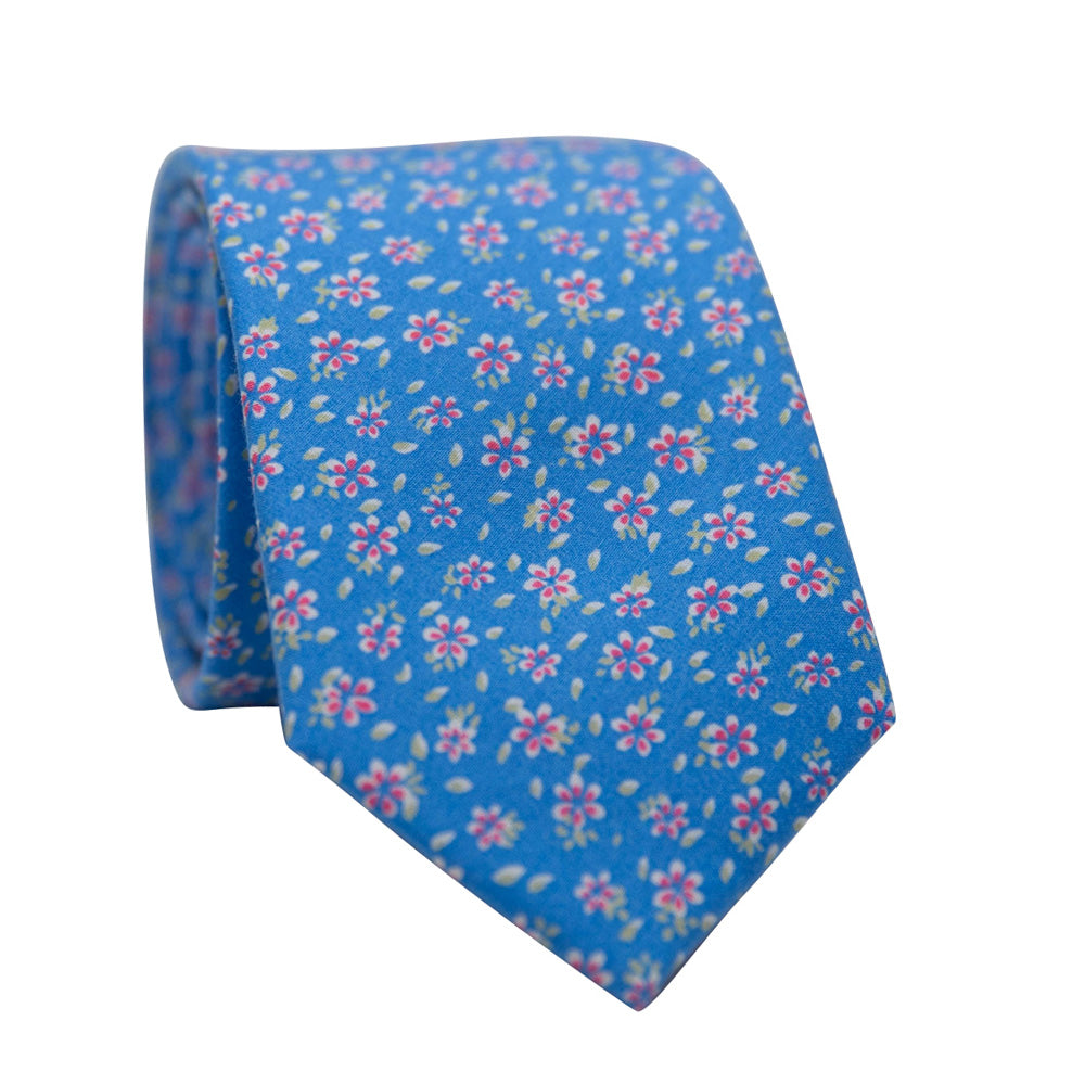 DAZI Primrose Tie. Blue background with small pink flowers and green leaves. 