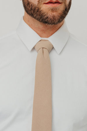 Sand tie worn with a white shirt.