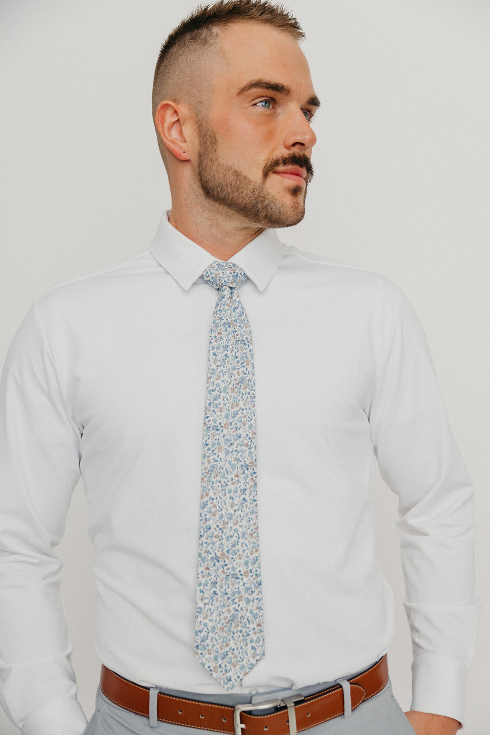 Scorpion Grass tie worn with a white shirt, brown belt and gray pants.
