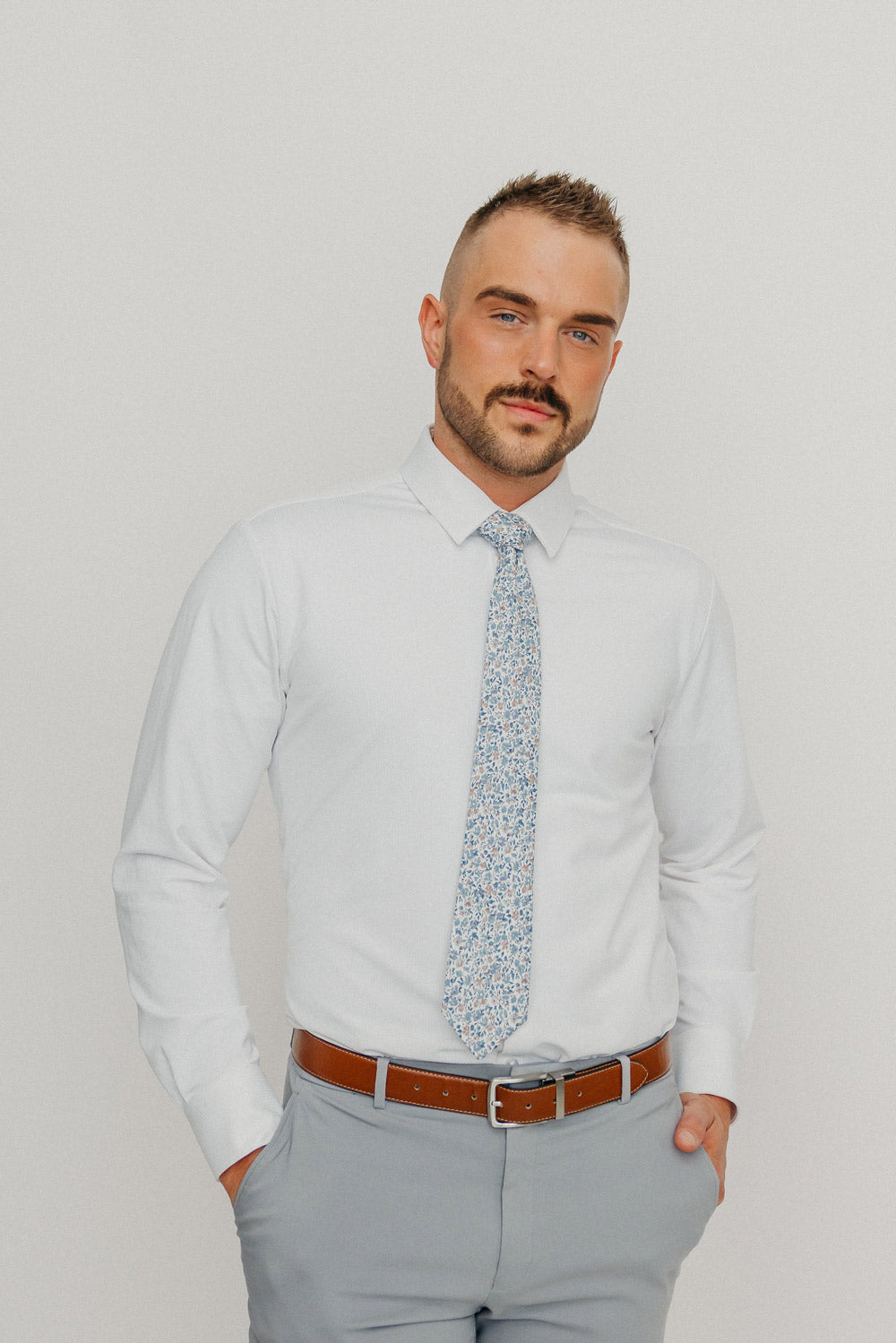 Scorpion Grass tie worn with a white shirt, brown belt and gray pants.
