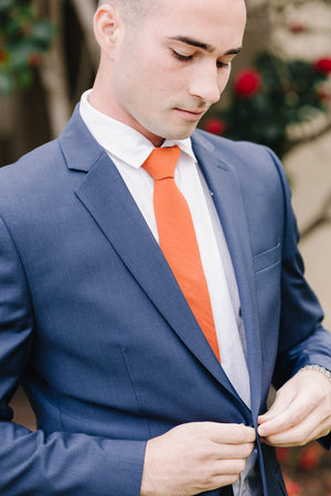 Tangerine tie worn with a white shirt and blue suit. 