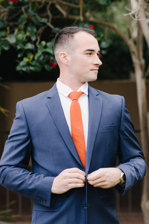 Tangerine tie worn with a white shirt and blue suit. 