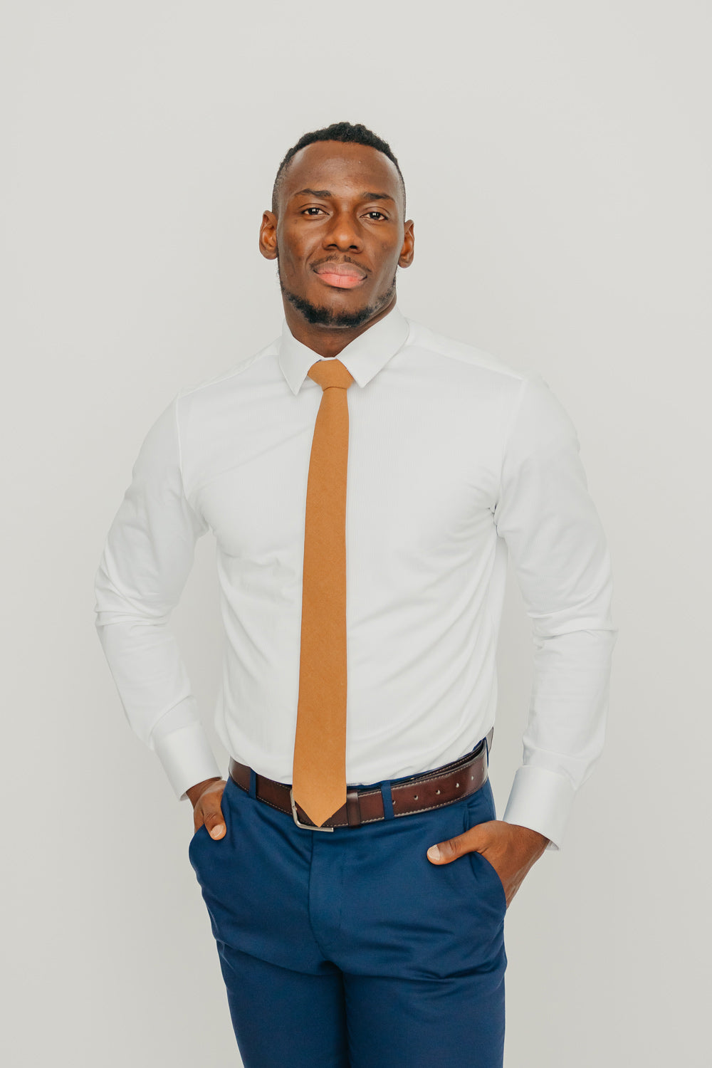 Timber tie worn with a white shirt, brown belt and blue pants.