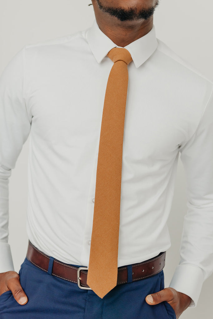 Timber tie worn with a white shirt, brown belt and blue pants.
