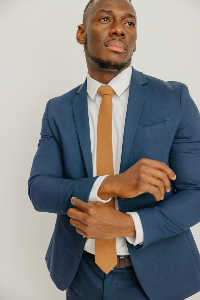 Timber tie worn with a white shirt, brown belt and blue suit.