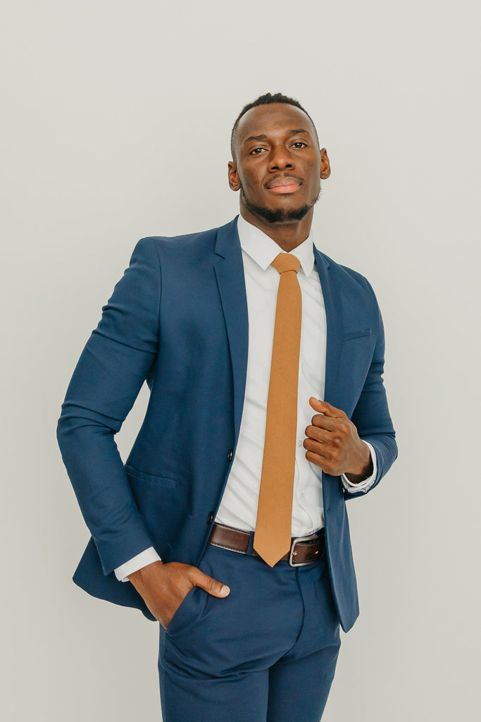 Timber tie worn with a white shirt, brown belt and blue suit.