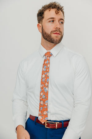 Western tie worn with a white shirt, brown belt and blue pants.
