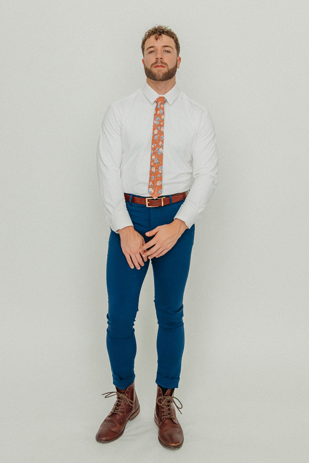 Western tie worn with a white shirt, brown belt and blue pants.