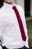 Wine necktie worn with a white shirt and blue pants. 