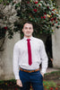 Wine necktie worn with a white shirt and blue pants. 