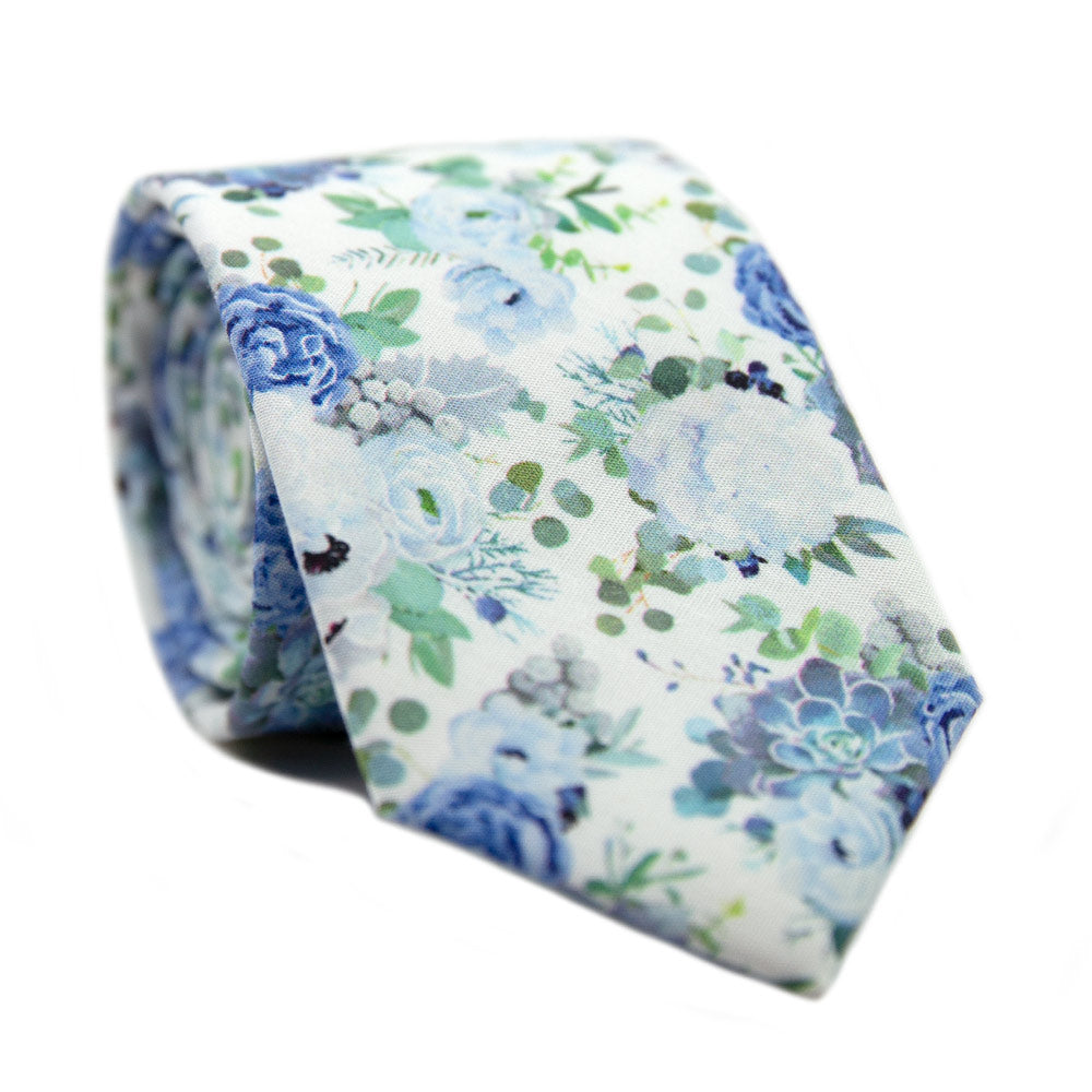 Arctic Ice Skinny Tie. White background with dusty blue and navy blue flowers and succulents with green leaves.
