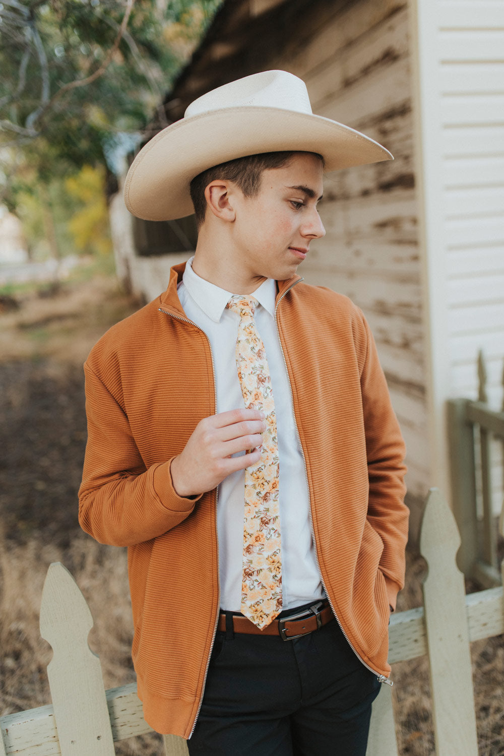 Autumn Cascade Tie worn with a white shirt, orange zip cardigan and black pants. Model is also wearing a cowboy hat.