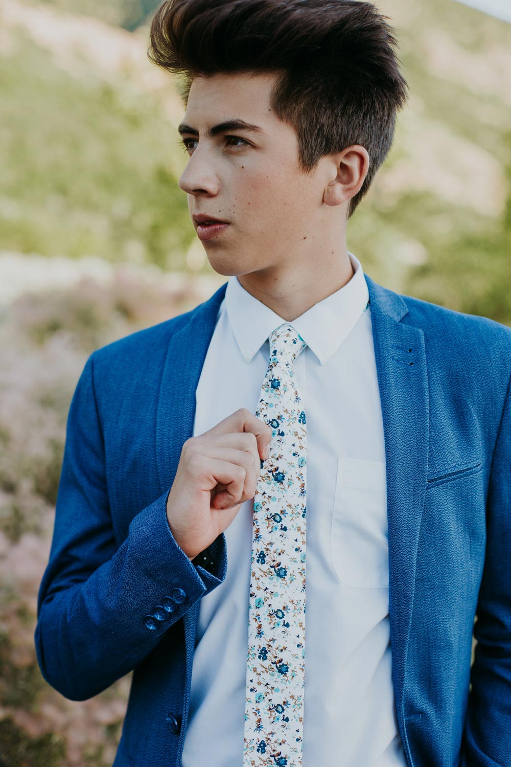 Blue Bloom tie worn with a white shirt and navy blue suit jacket.