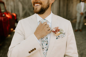 Blue bloom tie worn with a white shirt and light tan suit.