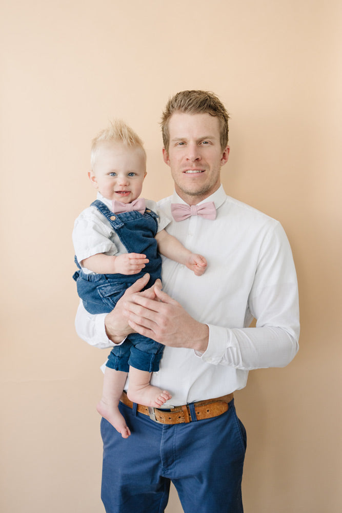 Blush Pre-Tied Bow Ties worn by dad and son wearing white shirts and blue pants. 