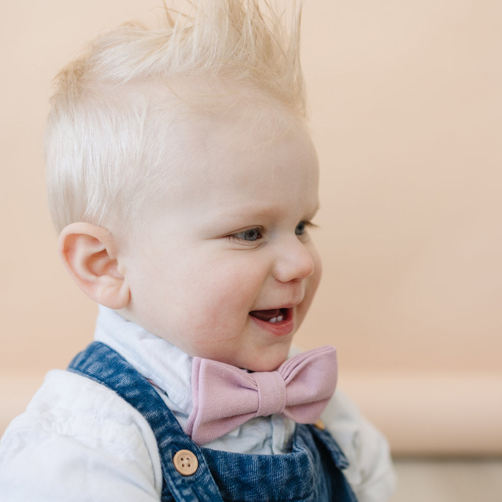 Blush Pre-Tied Bow Tie worn by baby with white shirt and blue denim overalls. 