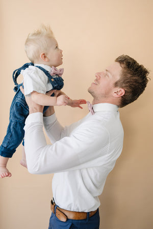 Blush Pre-Tied Bow Ties worn by dad and son wearing white shirts and blue pants. 