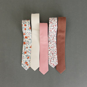 Five skinny ties laying flat next to one another.