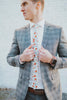 Citrus tie worn with a white shirt, gray plaid blazer and gray pants.