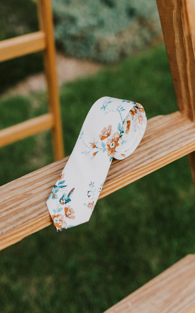 Copper Blooms tie rolled up and sitting on a wooden ladder.