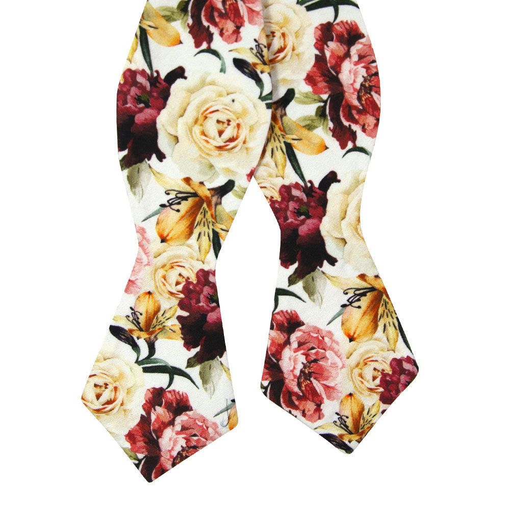 Coral Void Self Tie Bow Tie. White background with ivory, maroon and gold flowers and green stems and leaves. 