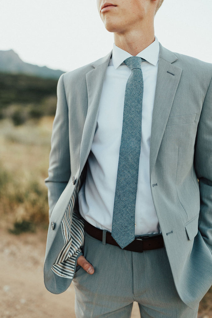 Crew tie worn with white shirt and gray suit.