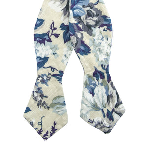 Dreamy Fields Self Tie Bow Tie. Cream background with dusty blue, white and gray flowers with navy blue and purple leaves.