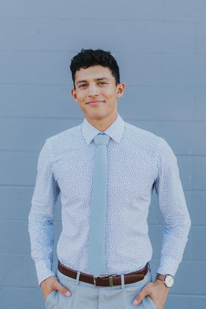 Dressing in a light blue shirt, gray pants, a colorful pattern tie, a young  black businessman is standing outside an office building, looking forward  Stock Photo - Alamy