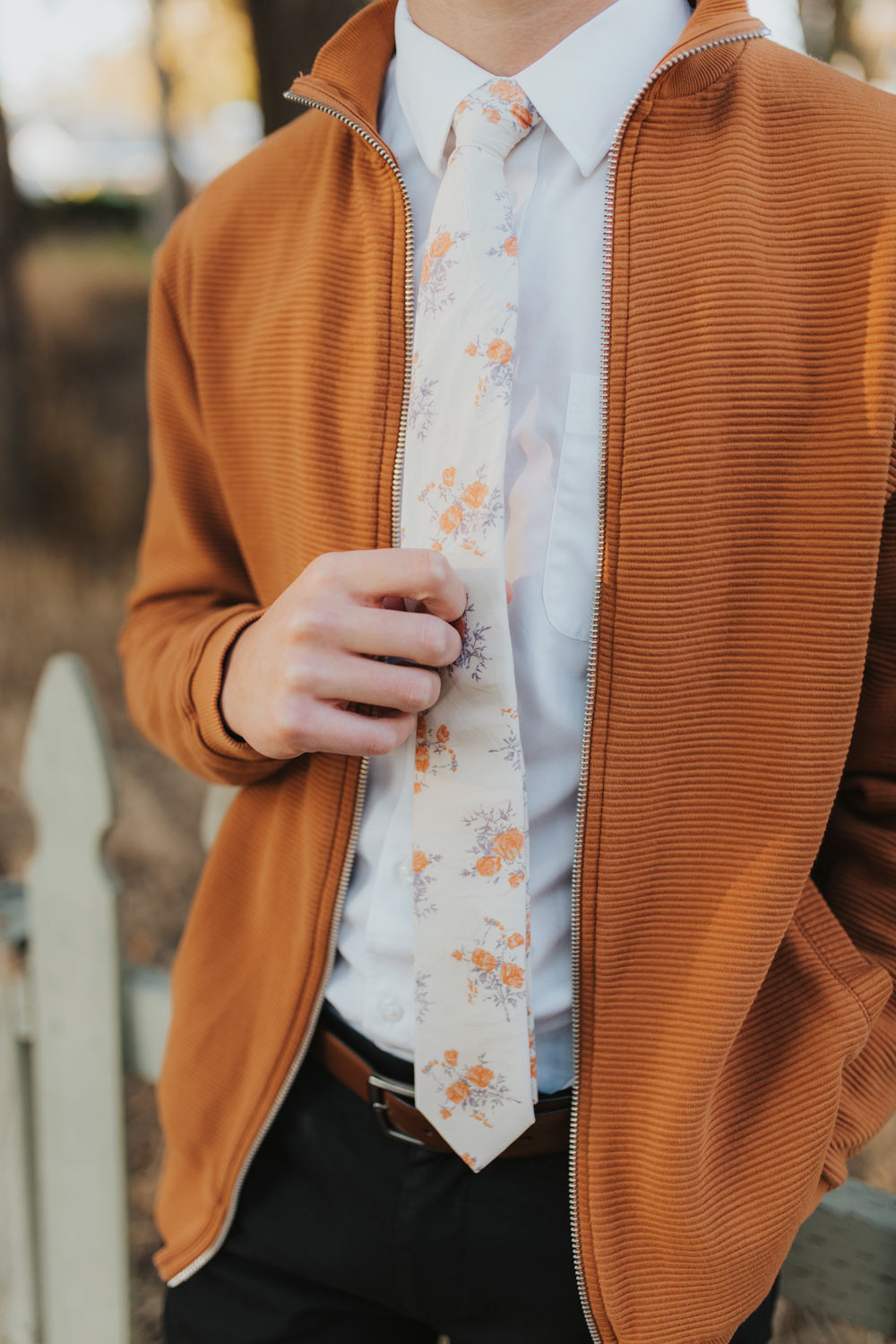 Harvest Blossom Tie worn with a white shirt, orange cardigan and black pants.