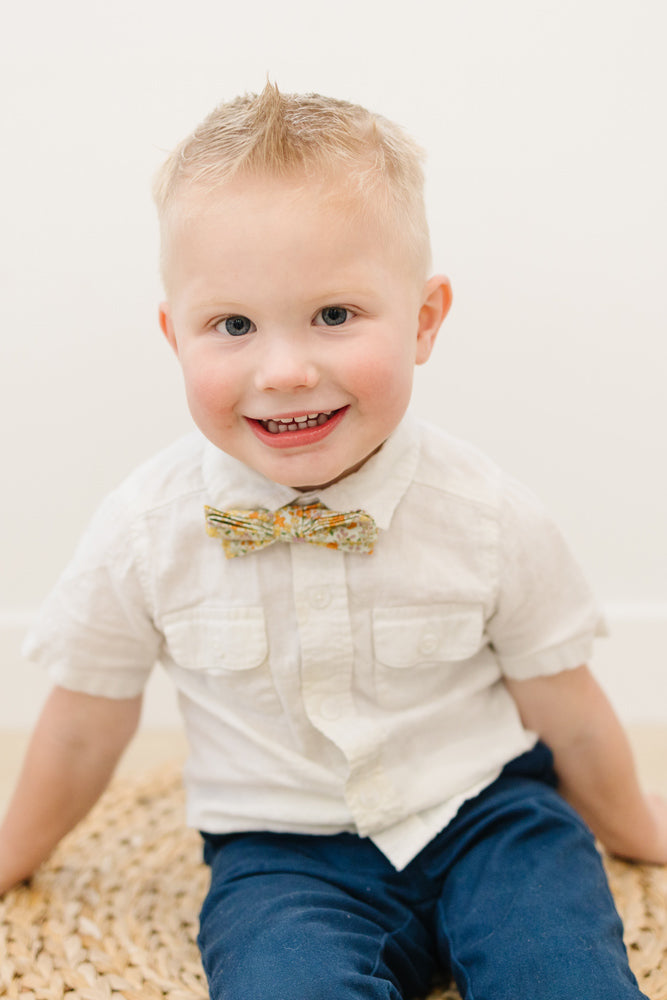 Honey pre-tied bow tie worn with a white shirt and blue pants.
